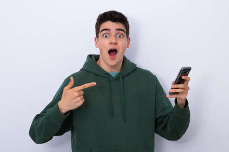 isolated teenager showing mobile phone with surprise or amazement