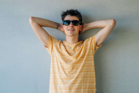 relaxed teen boy in sunglasses leaning on the wallの写真素材