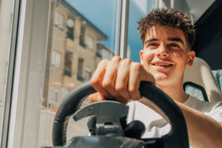 teenage boy playing with steering wheel racing or driving gamesの写真素材