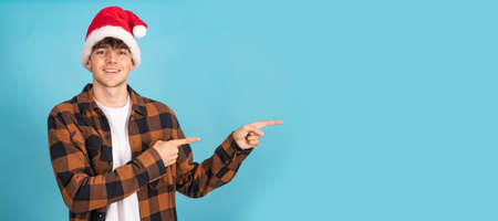 young man with santa claus hat isolated on blue colored background