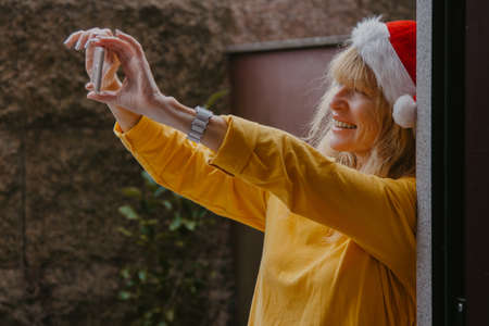 woman at home with santa claus hat at christmas with mobile phoneの写真素材