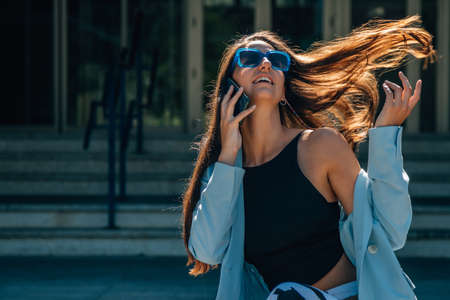 girl with hair in the wind in fashion talking on mobile phoneの写真素材