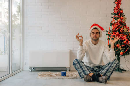 man at home christmas with santa claus hat and yoga poseの写真素材