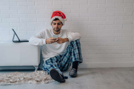 man at home with mobile phone and laptop at christmasの写真素材