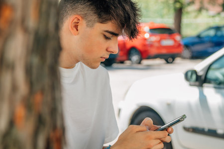 portrait of teenage boy with mobile phone outdoorsの写真素材