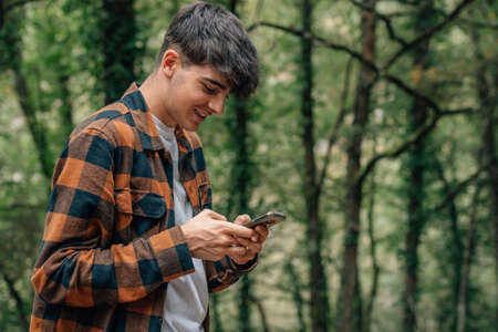 adolescent male with mobile phone in autumn outdoorsの写真素材