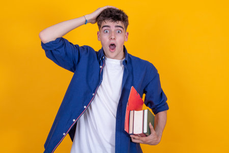 teenager boy with books surprised isolated on backgroundの写真素材
