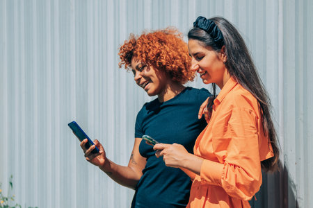 couple of girls on the street with mobile phonesの写真素材