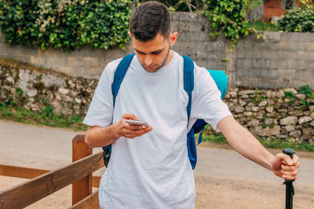 young man traveling or hiking with backpack looking at mobile phoneの写真素材