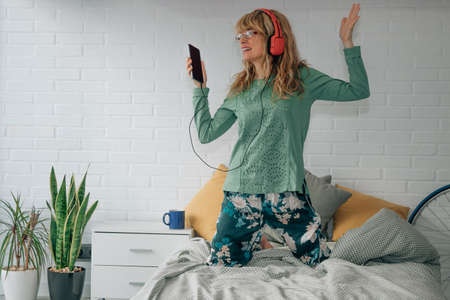 happy woman listening to music at home with headphones and mobile phoneの写真素材