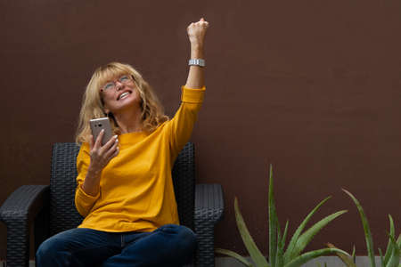 woman with mobile phone celebrating successの写真素材