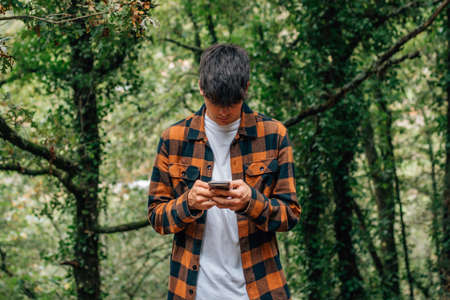 teenager looking at mobile phone outdoors with autumn stylingの写真素材