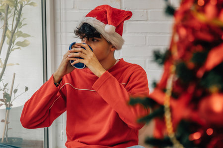teenager at home with christmas tree and cupの写真素材