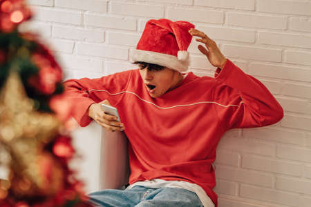 man at home for christmas with mobile phone and surprised expression