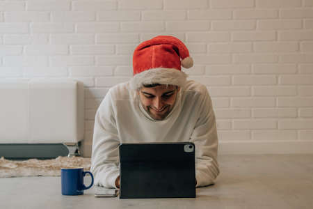 man at home at christmas with santa claus hat and computer