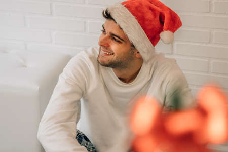 portrait of smiling man at christmas with santa claus hat at home