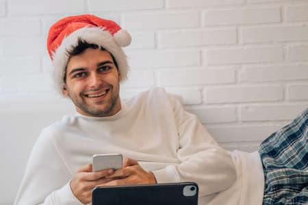 man at home with mobile phone and computer at christmasの写真素材