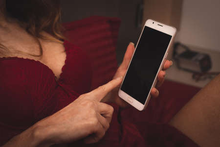 close-up of woman's hands with mobile phone and lingerieの写真素材