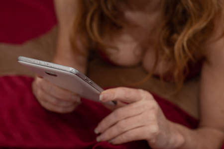close-up of woman's hands with mobile phone and lingerie