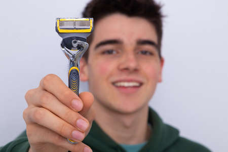teen boy with razor on white background