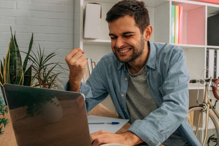 man with computer and success expression at desk