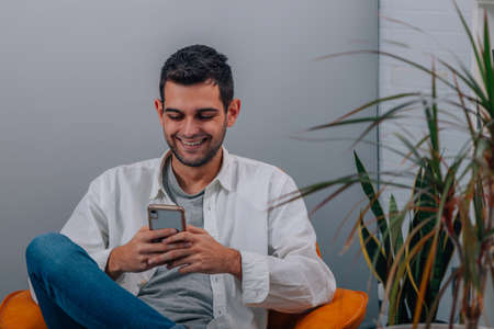 young man at home sitting on sofa looking at mobile phoneの写真素材