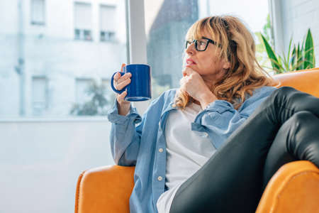 middle-aged woman at home drinking coffeeの写真素材