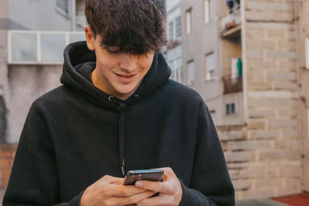teenager boy with mobile phone or smartphone in the streetの写真素材
