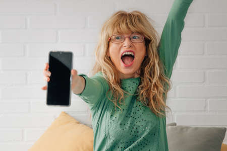 mid adult woman with mobile phone celebrating success or happinessの写真素材