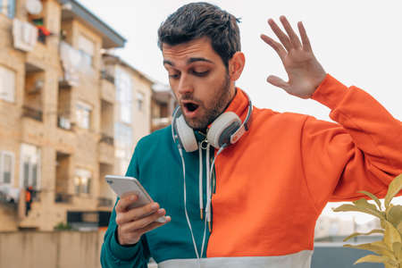 young man on the street looking surprised at the mobile phone