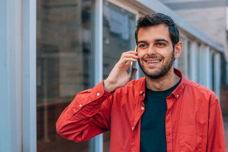 young man walking down the street talking on mobile phone