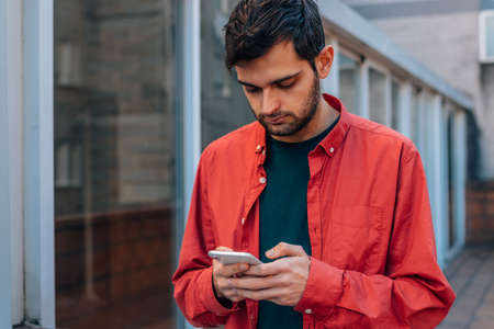 man with mobile phone in the street with red shirt in casual styleの写真素材