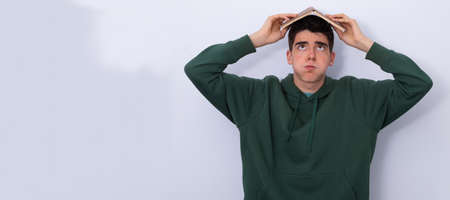 isolated student with book and expression of tiredness or stress overwhelmedの写真素材