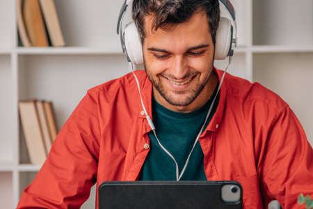 bearded young man in headphones working with laptop