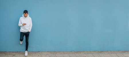 young man with mobile phone on the street wallの写真素材