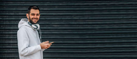 young man with mobile phone and headphones on the street