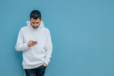 fashionable young man with mobile phone on blue street wall