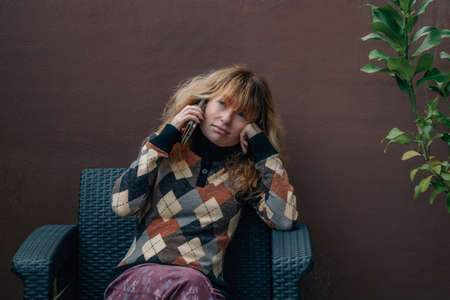 middle aged woman at home talking on mobile phone or smartphoneの写真素材