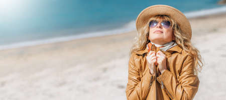 dressed middle-aged woman enjoying on the beachの写真素材
