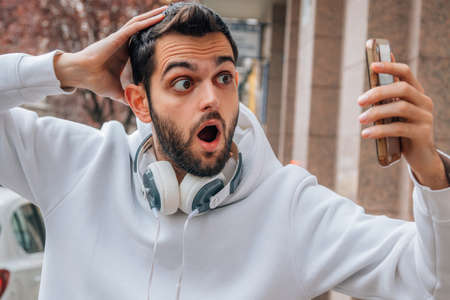 scared man looking at mobile phone in the street