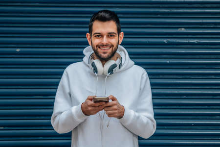 young man with mobile phone and headphones on the street