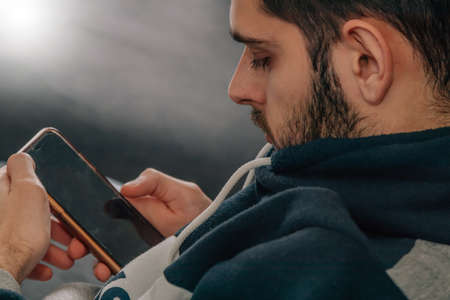 man on the sofa at home looking at the mobile phoneの写真素材