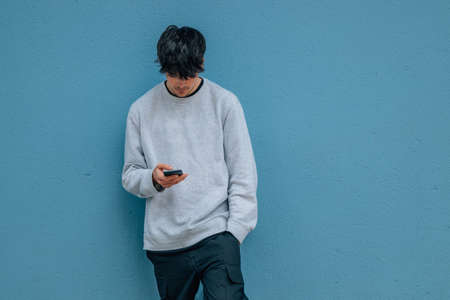 young man with mobile phone on street wall with copy-spaceの写真素材