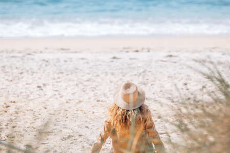 girl with hat sitting on the sand on the beachの写真素材