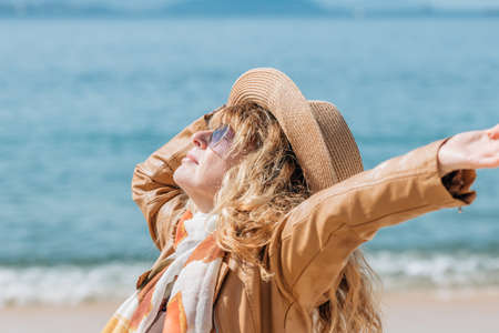 dressed middle-aged woman enjoying on the beachの写真素材