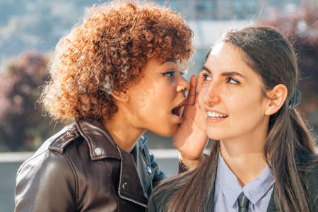 girls gossiping or whispering secret in the ear