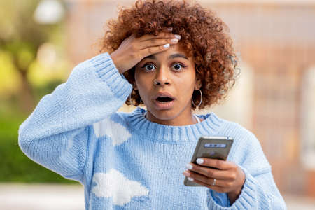 surprised or amazed girl with mobile phoneの写真素材