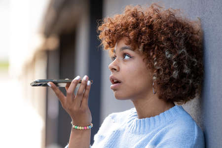 girl sending a voice message with mobile phone in the streetの写真素材