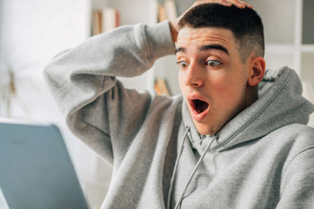 astonished young man looking at the computerの写真素材
