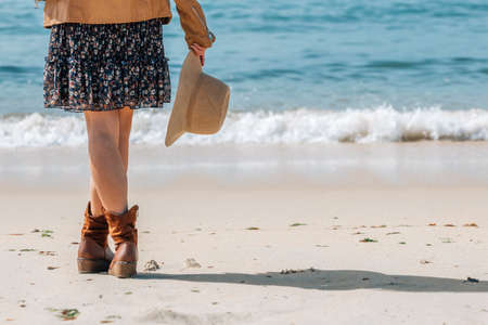 girl with hat on the beach looking at the sea